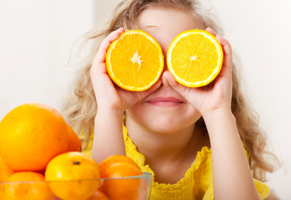 Kind mit Orangen auf den Augen